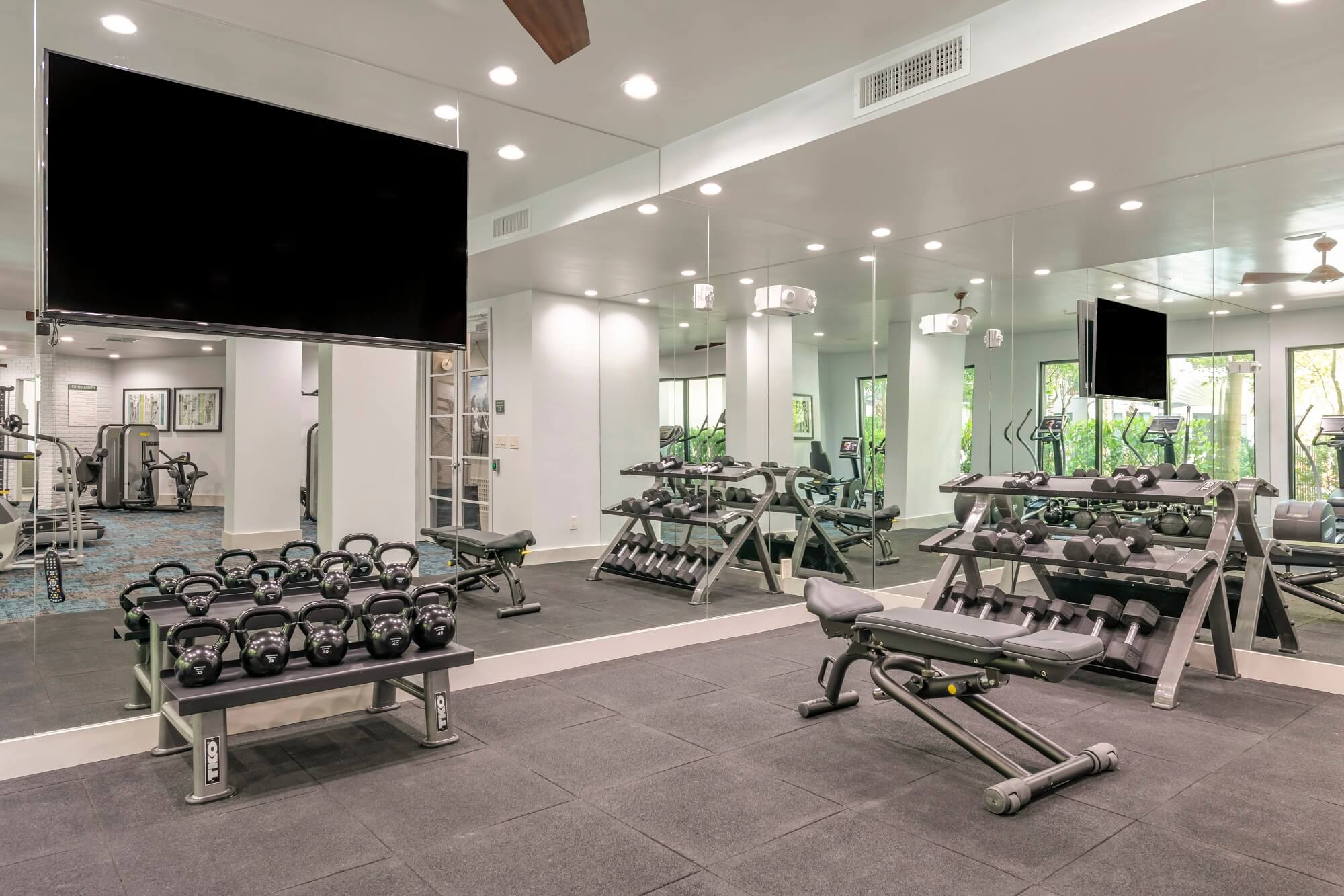 Modern gym at Bell Lighthouse Point Resort Apartments in Pompano Beach, FL with weights and equipment.